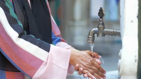 woman washing hands at a public fountain