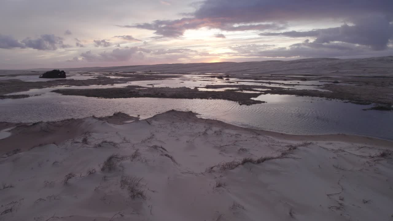 drone vuela sobre dos personas en la playa de dunas de arena de stockton durante la puesta de sol en nueva gales del sur, australia