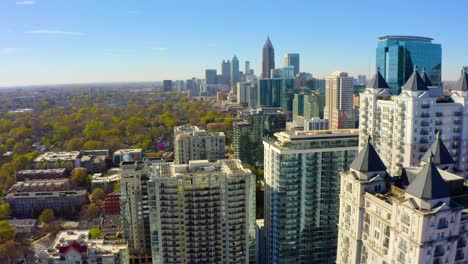 aerial drone shot slowly flying forward over residential buildings near piedmont park in midtown looking toward the skyscrapers in downtown atlanta, georgia on a sunny day with blue skies