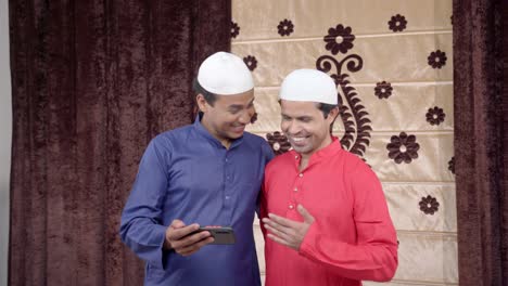 two muslim men watching videos on mobile phone