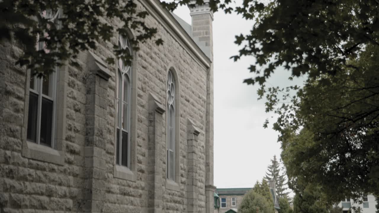 caminando por un camino de hormigón en medio del césped junto al exterior del edificio panoramizando para revelar el campanario de la st