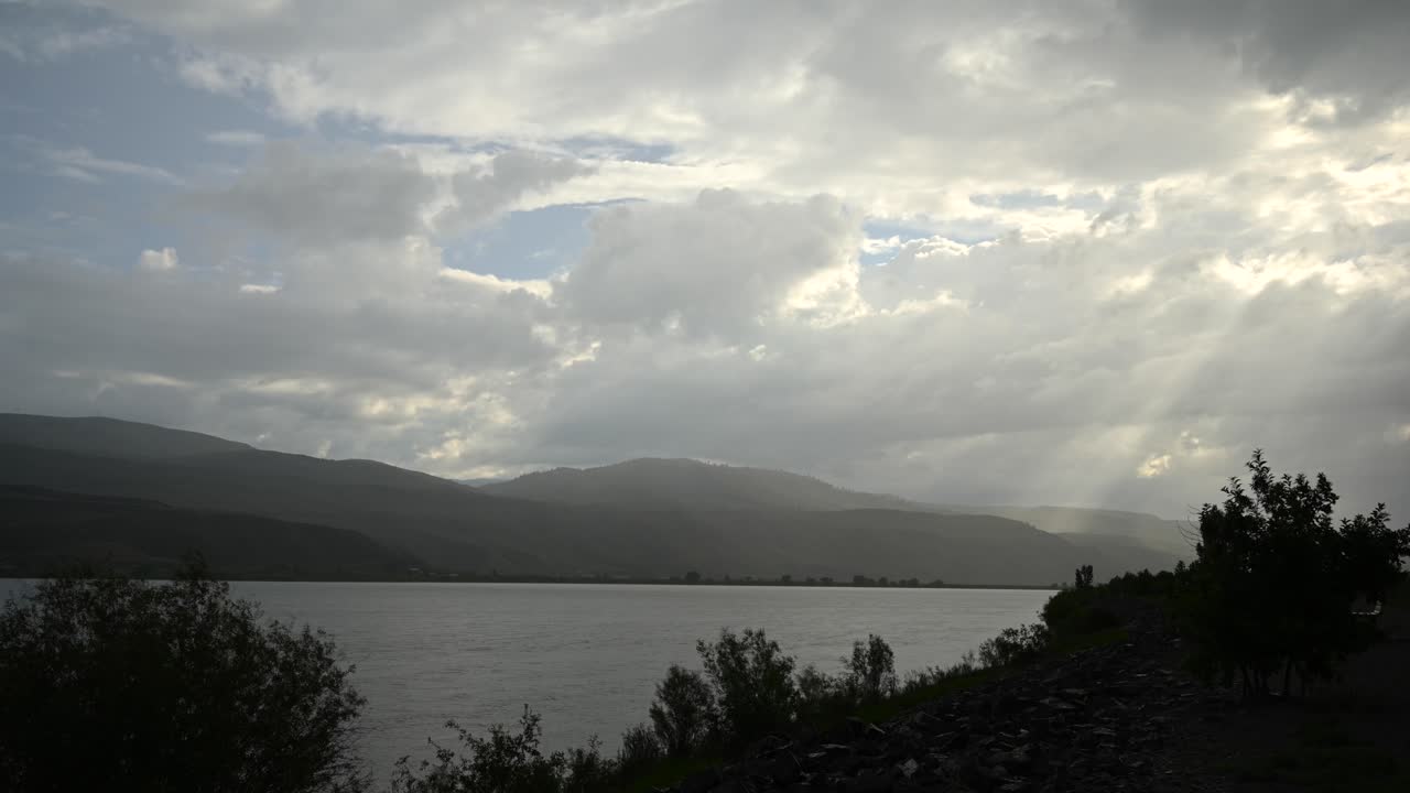 elegía de lapso de tiempo del río thompson: nubes de tormenta se reúnen sobre el horizonte de kamloops con rayos de sol