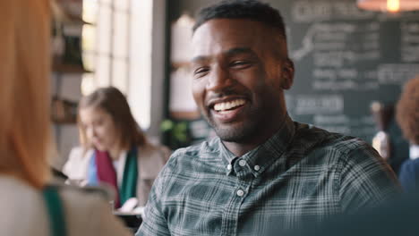 Atractivo-Hombre-Afroamericano-Charlando-Con-Un-Amigo-Tomando-Café-En-Una-Cafetería-Socializando-Disfrutando-De-Una-Conversación-Relajándose-En-Un-Restaurante