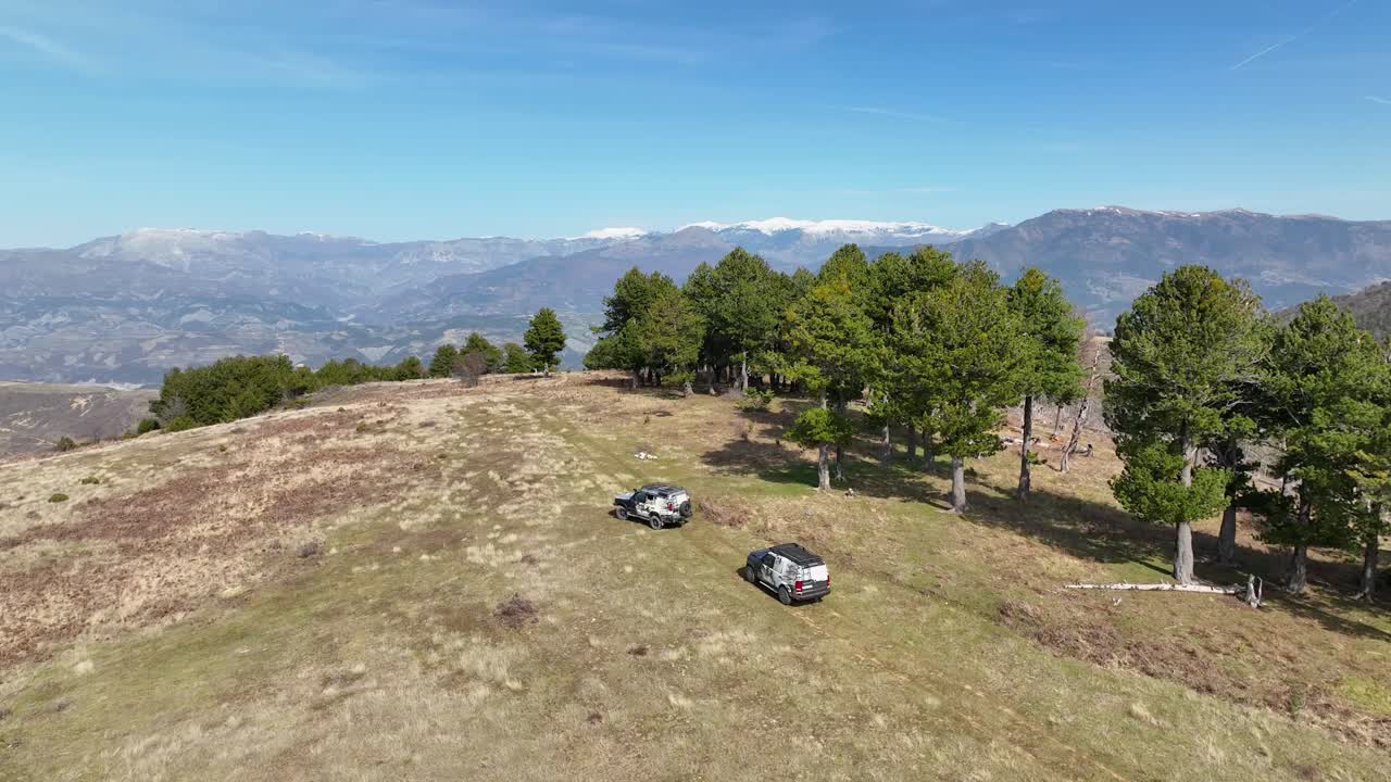 숲과 눈  ⁇ 인 산을 배경으로 언덕 꼭대기에 운전하는 두 대의 오프 로드 차량의 파노라마  ⁇
