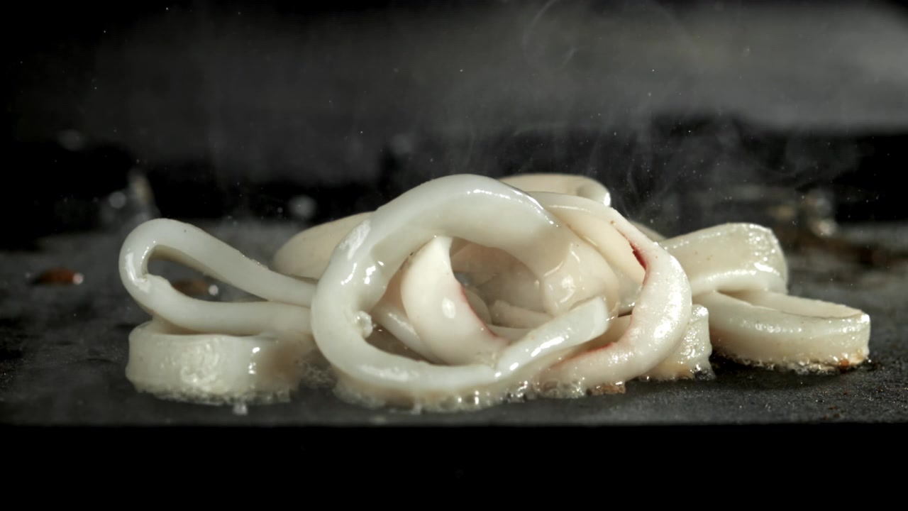 Anneaux de calamars frais grésillant sur une plancha chaude