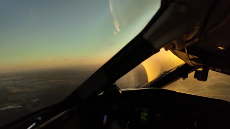 Pilot-POV-in-a-real-time-flight-at-sunset,-Captain-side,-with-a-dazzling-orange-sun-ahead-in-a-right-turn