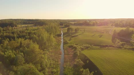 drone flying forward above stream in northern europe park at sunset