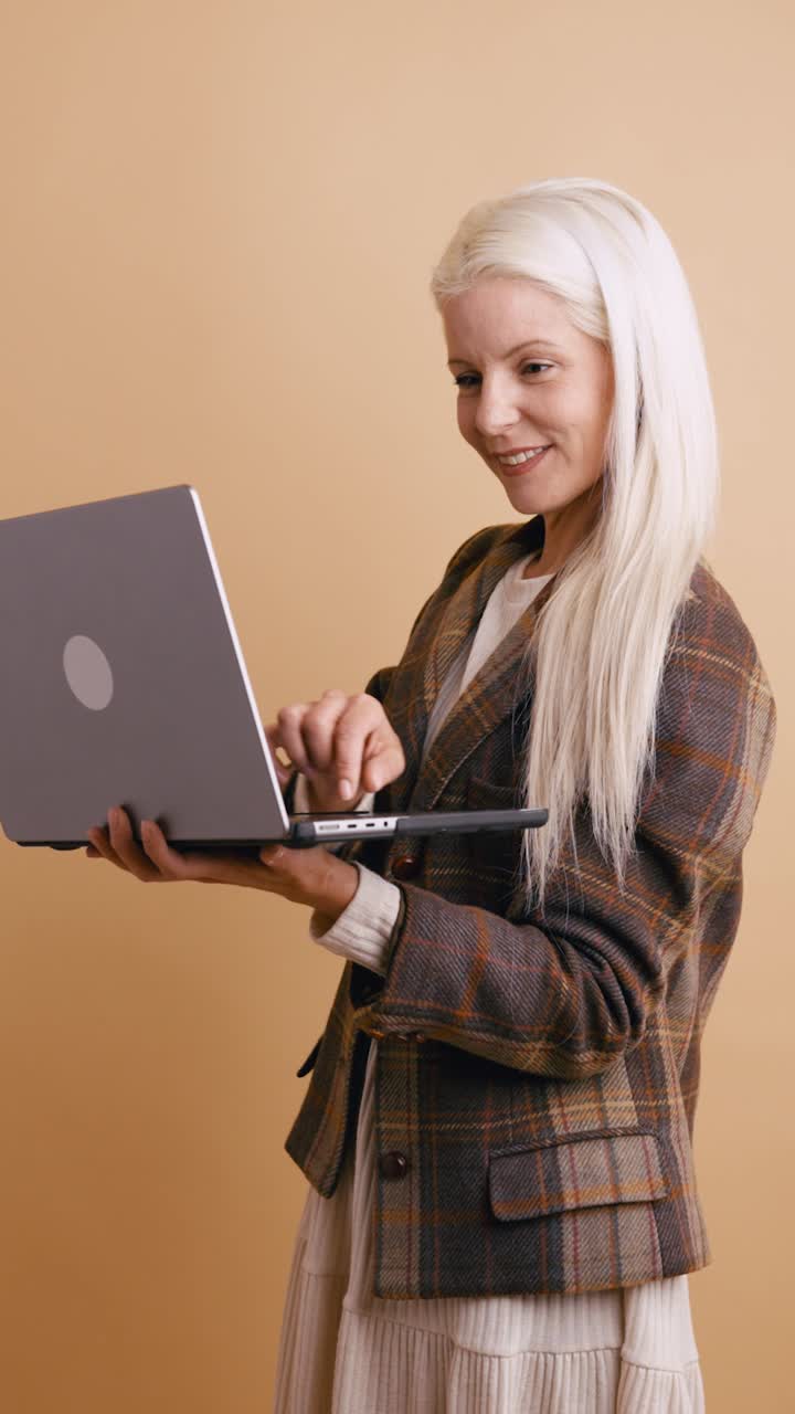 Donna bionda felice che lavora al laptop in studio