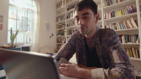 young man chatting on web call on laptop at home