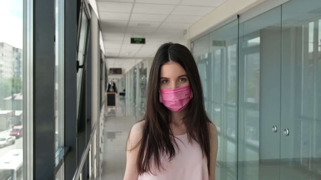 Young Woman Wearing a Pink Face Mask in a Hallway