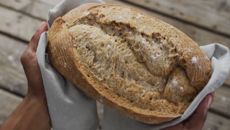 video von brot in den händen auf einer hölzernen arbeitsplatte, von oben gesehen