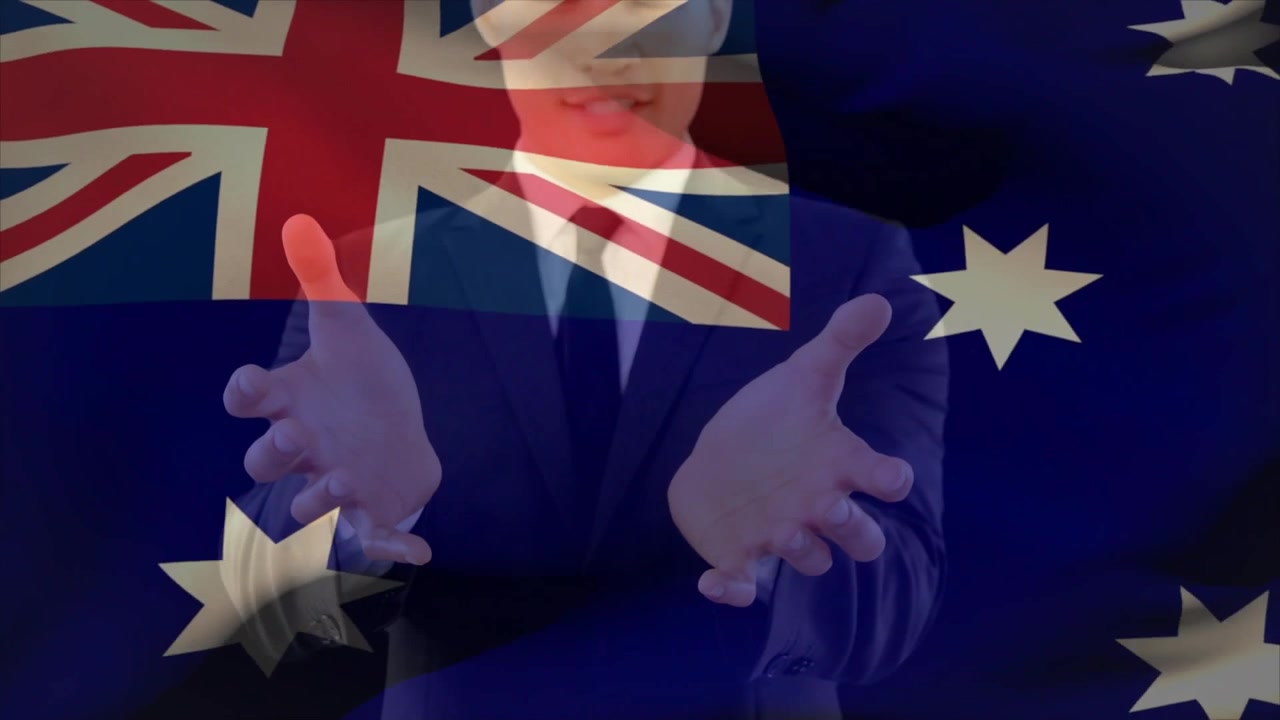 Hombre de pie dando un discurso, con las palmas abiertas, enfatizando un mensaje político con la bandera australiana superpuesta