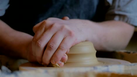 professional male potter working with clay on potter's wheel