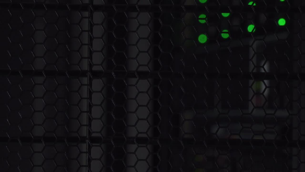 Data servers sitting behind a protective black mesh screen slowly illuminated