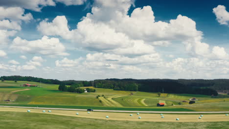 A-dark-car-driving-down-a-scenic-road-surrounded-by-lush-green-meadows-and-fields-in-this-sideways-moving-drone-footage