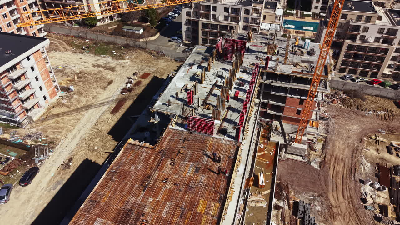 Obra de construcción con trabajadores y maquinaria en un edificio residencial en una ciudad, de día y bajo cielos despejados.