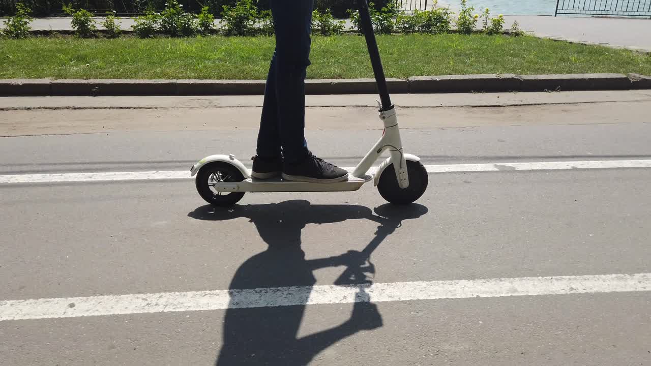 CHISINAU, MOLDOVA - JULY 9, 2019: Man riding a white electric scooter in Valea Morilor park. Lake on background