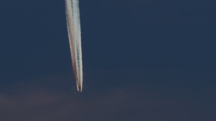 Aereo con scia di condensazione vivida nel cielo blu