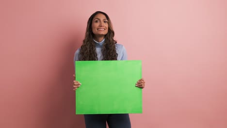 smiling woman holding a green board and gesturing thumb up