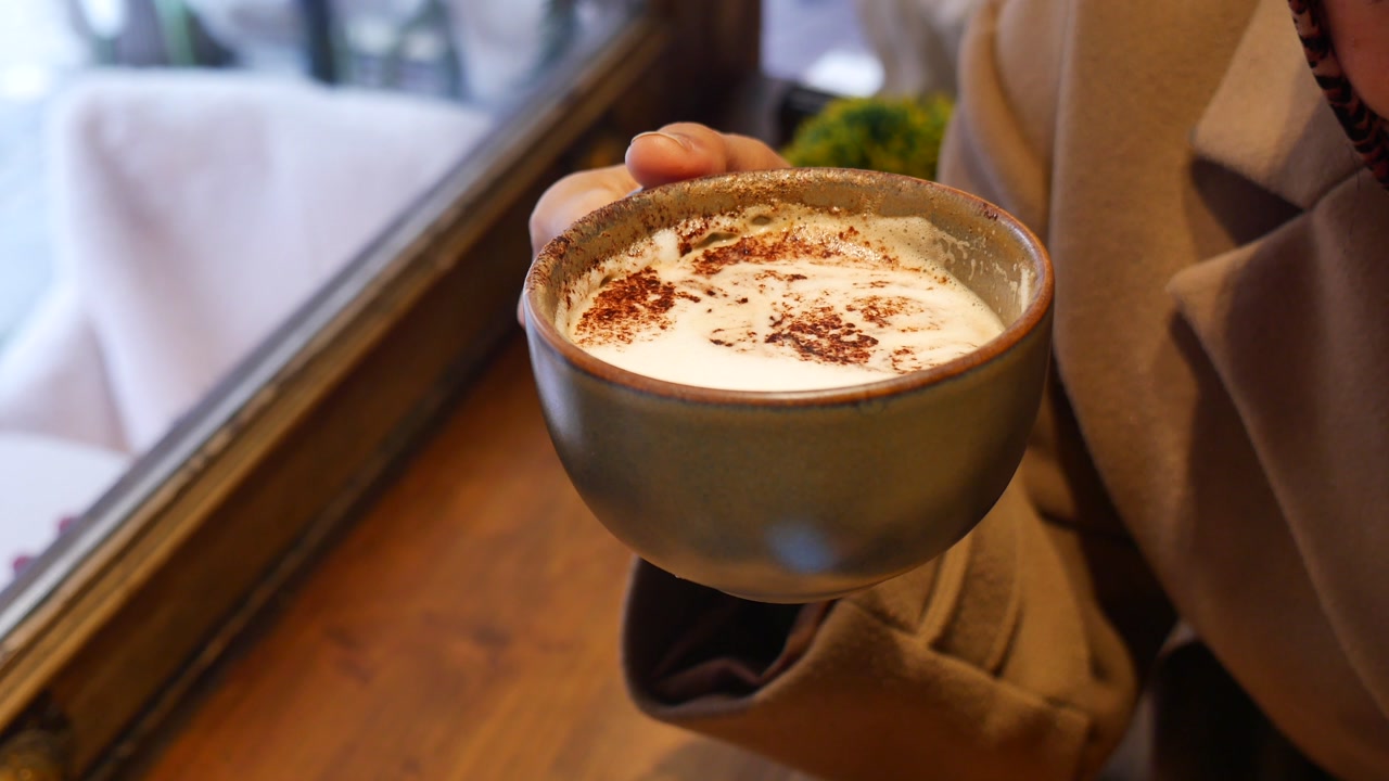 Close-up of Hand Holding a Warm Latte with Foam