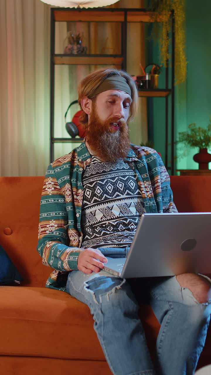 Mand sidder i sofaen derhjemme og kigger på kameraet, og foretager et videokonferenceopkald med venner eller familie