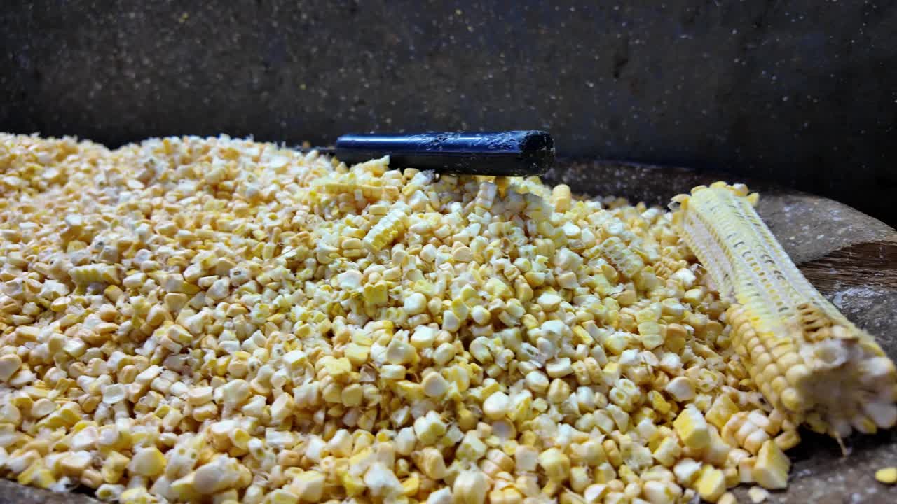 Close-up of peeled corn in a wooden tray with scattered kernels