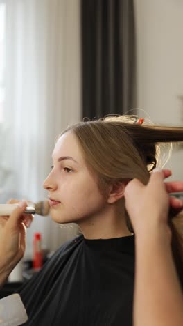 A woman getting her hair styled and makeup applied in a beauty salon