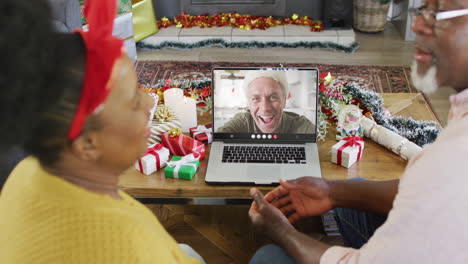 una pareja de ancianos afroamericanos tiene una llamada de video de navidad con un hombre caucásico feliz.