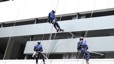 three workers cleaning a high-rise building using rope access