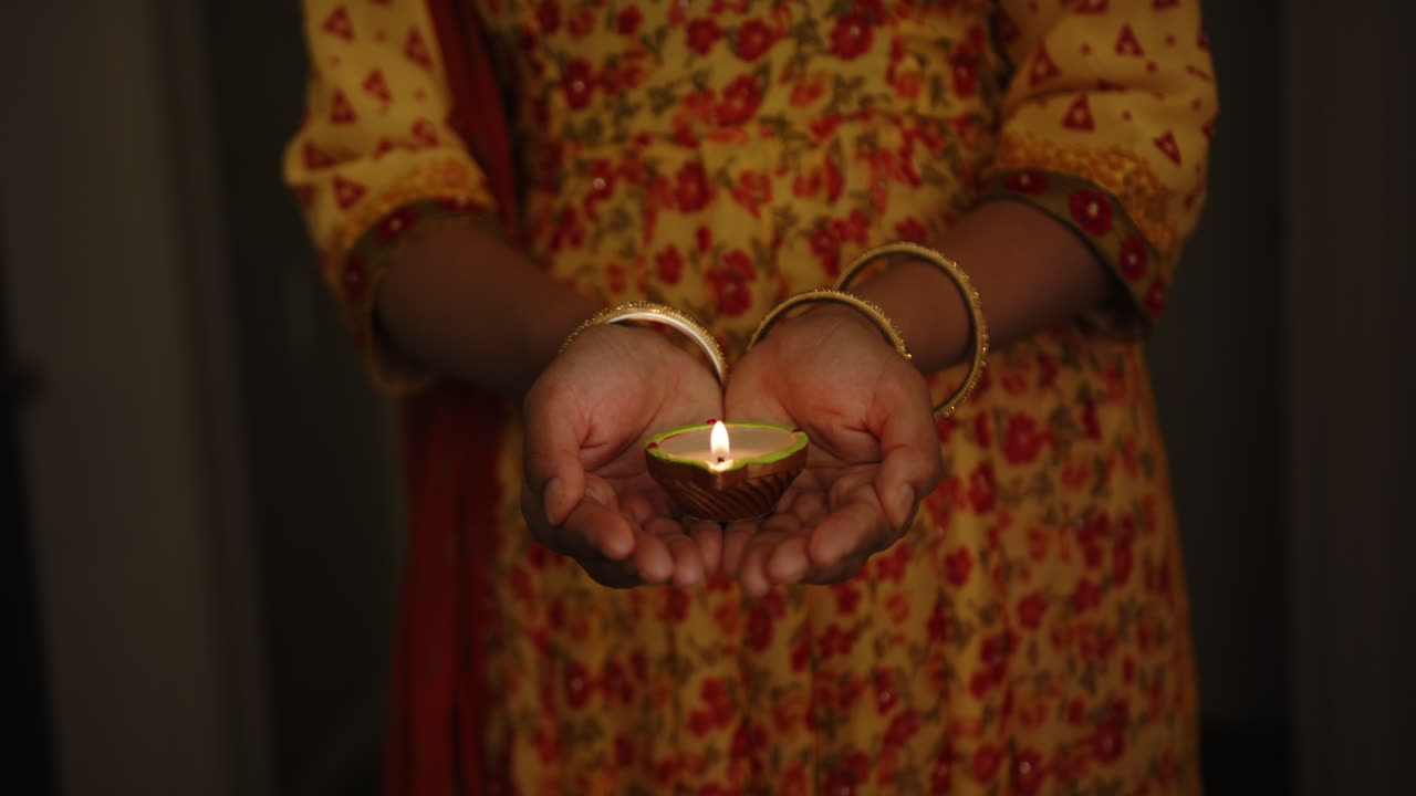 Holding lit diya, Indian woman in traditional sari celebrating Indian festival