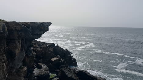 Klippe-Am-Meer-Mit-Einer-Angelrute-Zwischen-Den-Felsen-An-Einem-Grauen-Tag