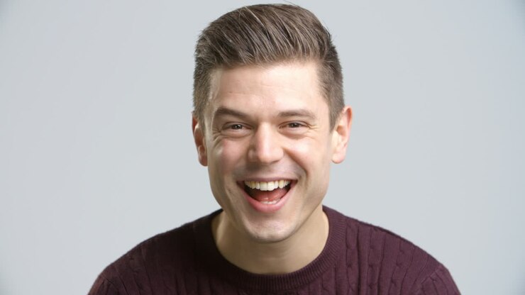 Studio Shot Of Young Man Smiling Into Camera In Slow Motion