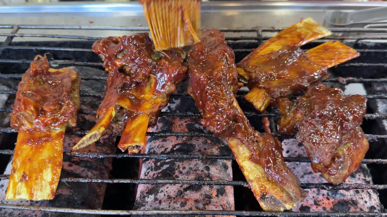 Spennellare costine marinate su una griglia calda per barbecue