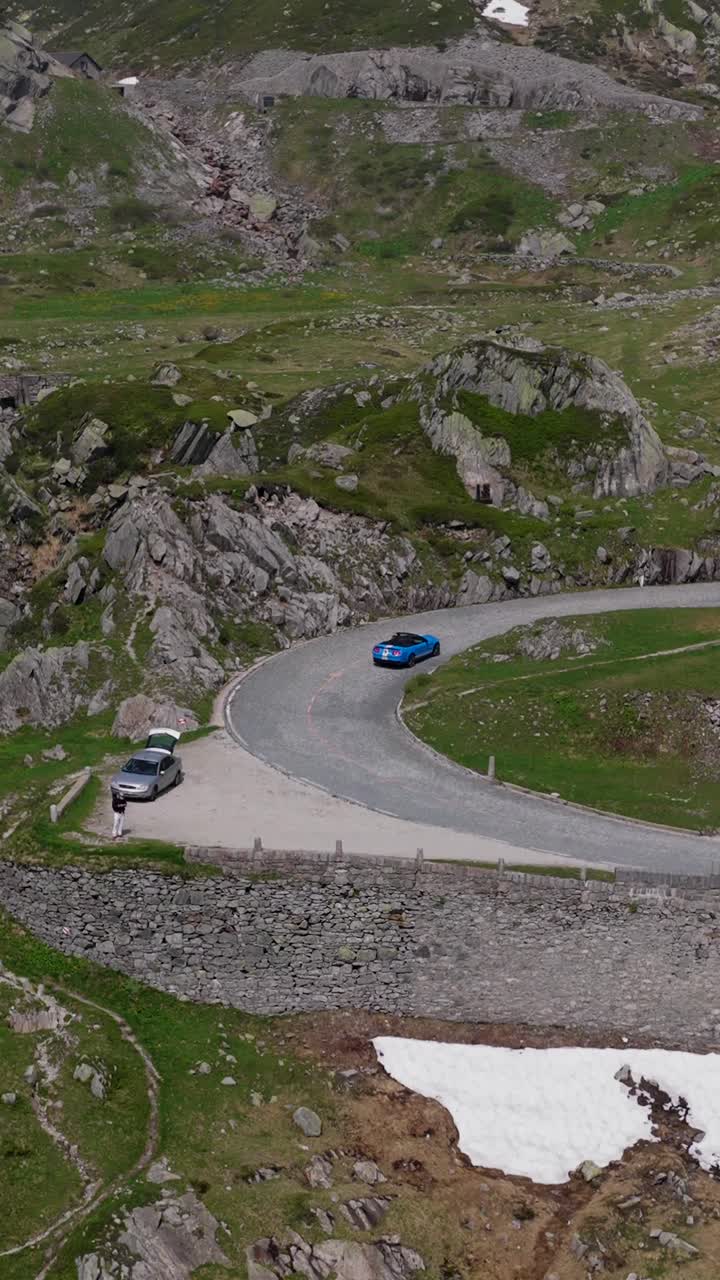 Epic aerial view of the winding Tremola Road snaking through the alpine slopes of Gotthard Pass, Switzerland, under a clear summer sky.