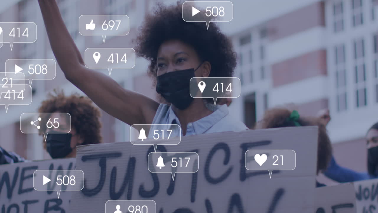 Animation of media icons over diverse people with face masks raising hands and protesting