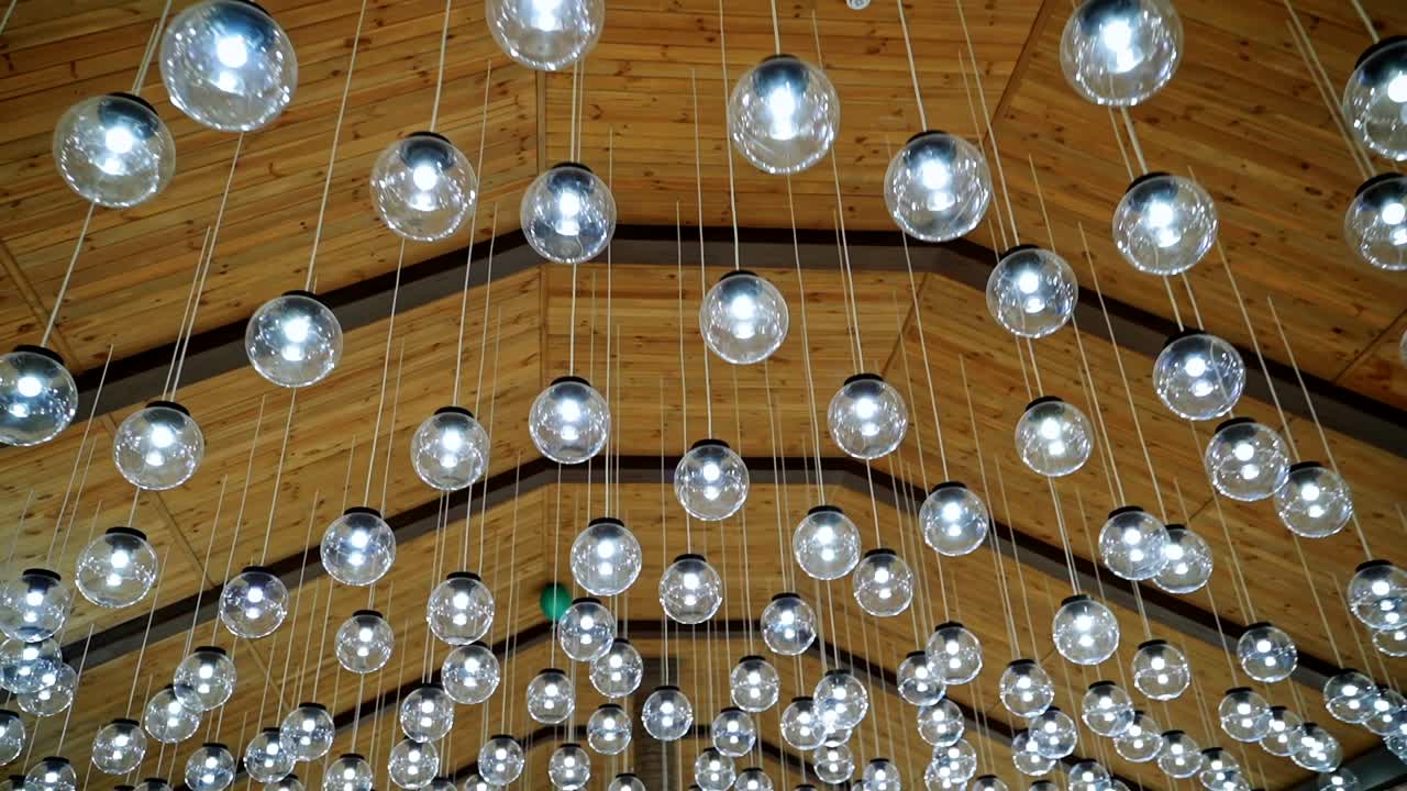 Luxury interior of glass light bulbs. Futuristic pendant lights of round shape. Many shiny balls on the ceiling background.