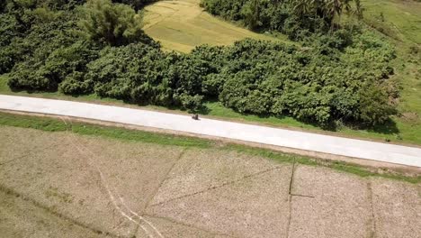 4k aerial drone view of couple riding on motorcycle in a tropical destination, el nido, palawan, philippines