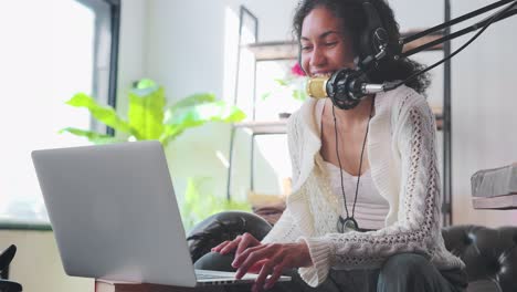 young african american woman with smile conducts audio podcast sits on couch