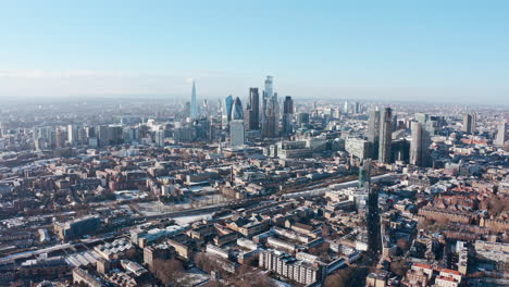 high dolly back drone shot over city of london skyscrapers from tower hamlets clear day after snow