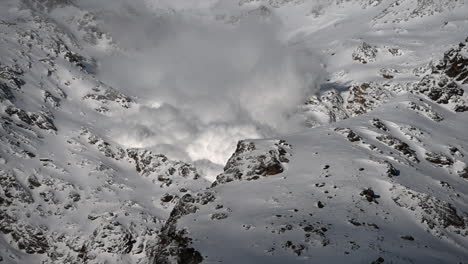 a foggy avalanche is going down a rocky mountain in the swiss alps, science phenomenon