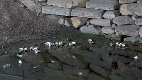 polystyrene cup floats in polluted water with plastic bottles, cans and waste