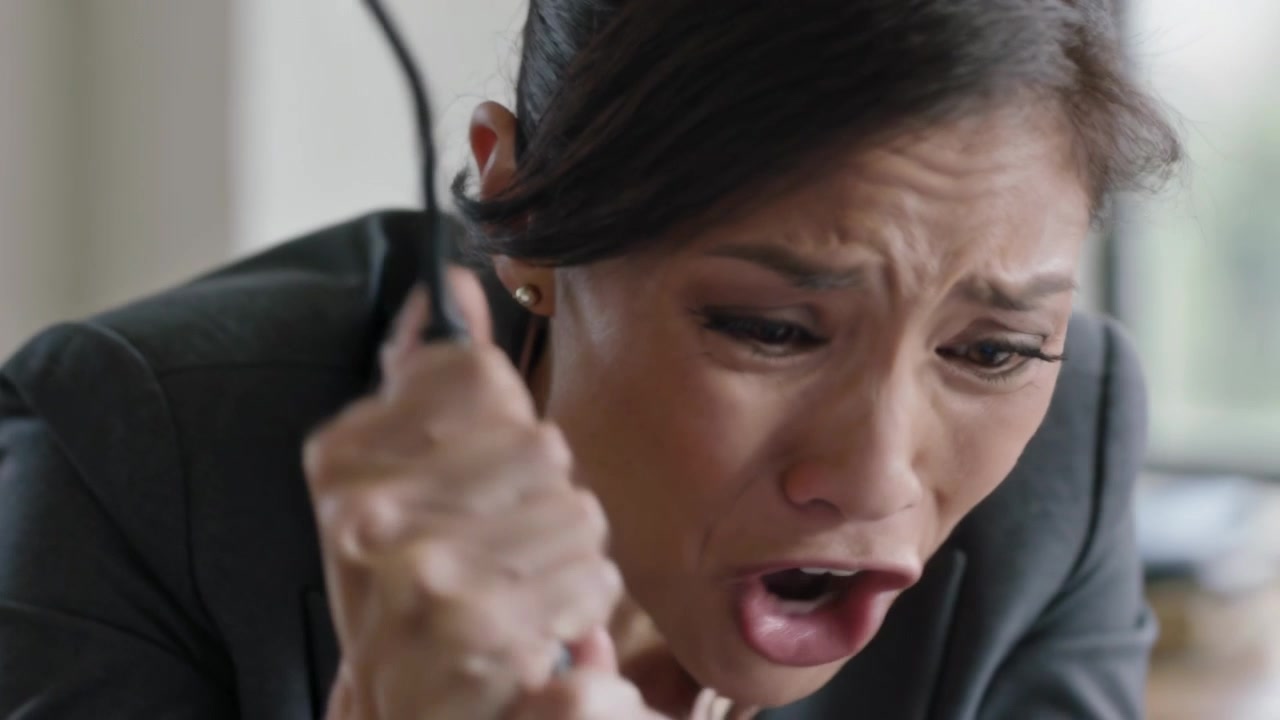 Gripping cord, office woman in dark blazer pulling and reacting to laptop alert at desk