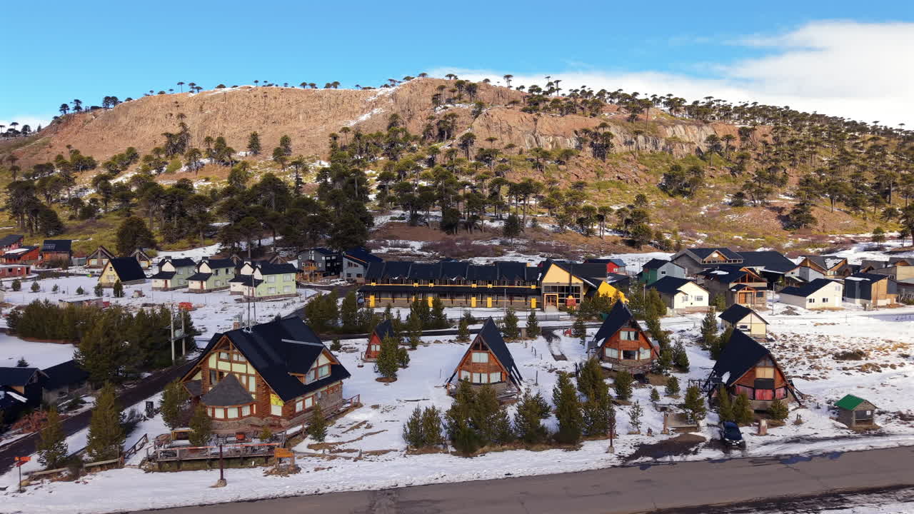 Snowy alpine village with A-frame chalets at the base of a mountain