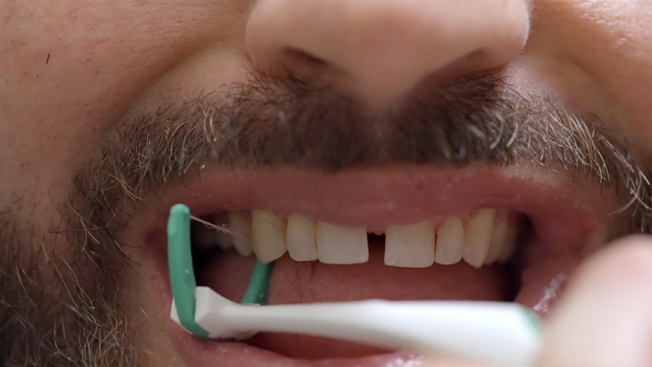 Close Up of Man's Mouth Using Y-Shaped Dental Flosser