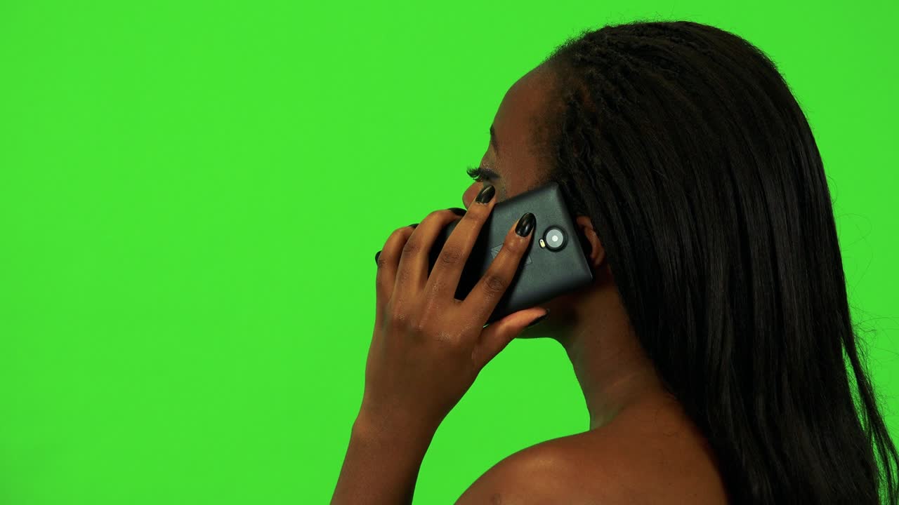 En ung svart kvinne ringer med en smarttelefon – nærbilde av hodet i profil – grønn skjerm-studio.