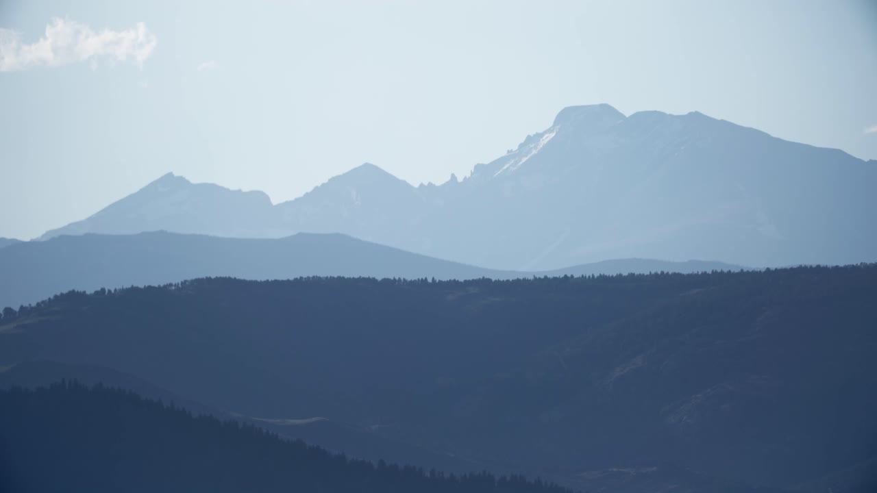 アメリカ合衆国コロラド州ボルダーのフラッグスタッフ山から見た、大気中のもやを通して重なり合うロッキー山脈のインディアンピークスとオーデュボン山