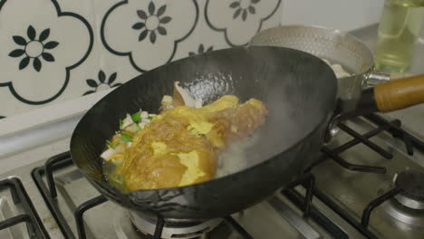 adding water into the abalone and egg dish inside big asian frying pan