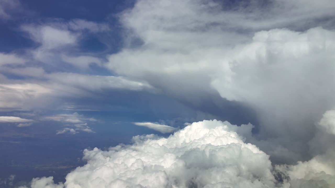 an immersive pilot’s view from inside a jet cockpit while flying at high altitude near massive and threatening storm clouds in a blue sky