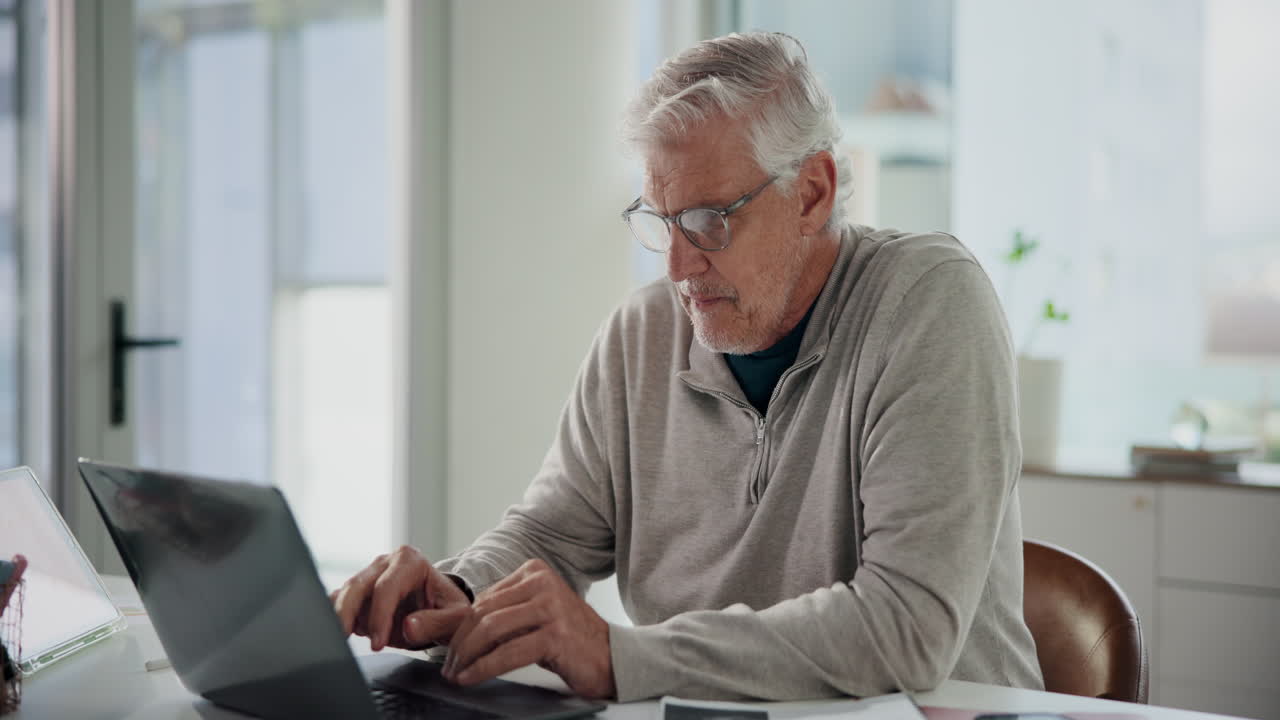 Senior man working on laptop with worried expression