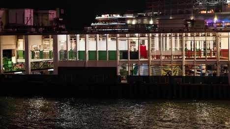 ferry approaches pier at night in hong kong